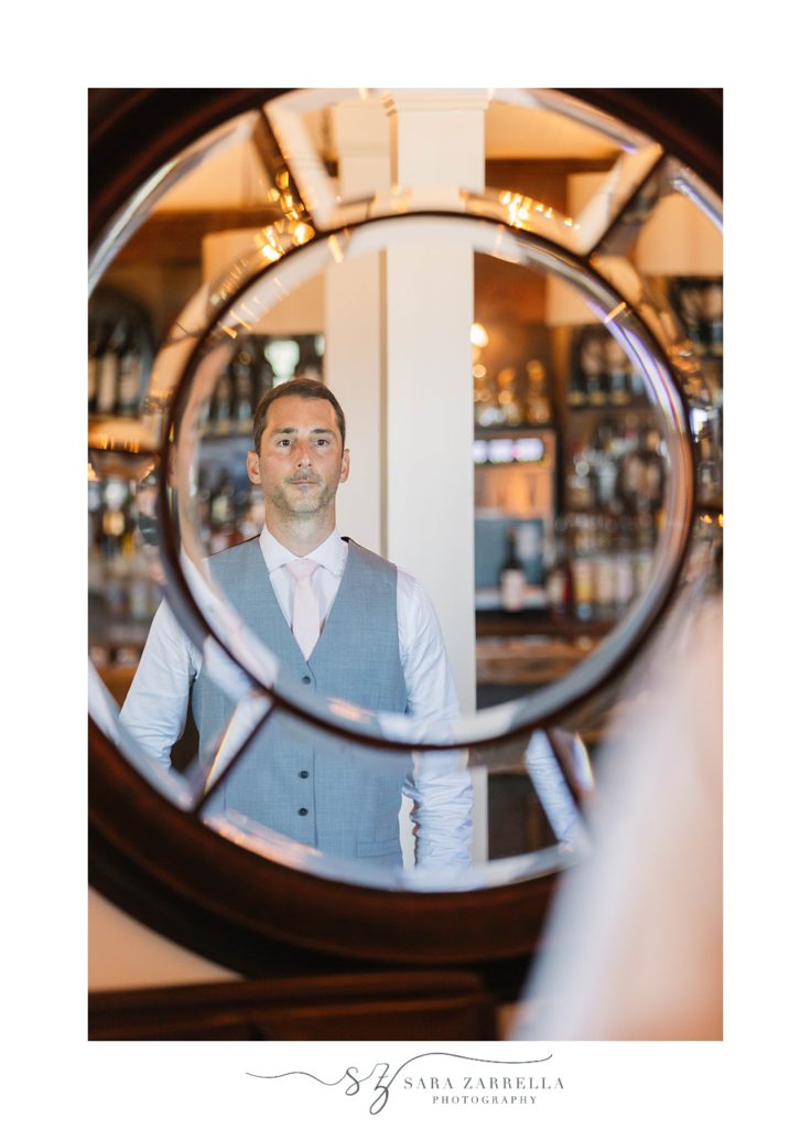 groom looks at reflection of mirror at Spring House Hotel 
