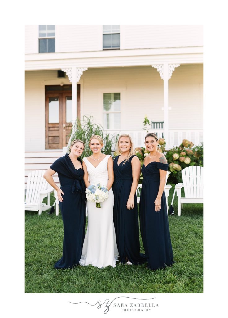 bride stands with bridesmaids in navy blue dresses