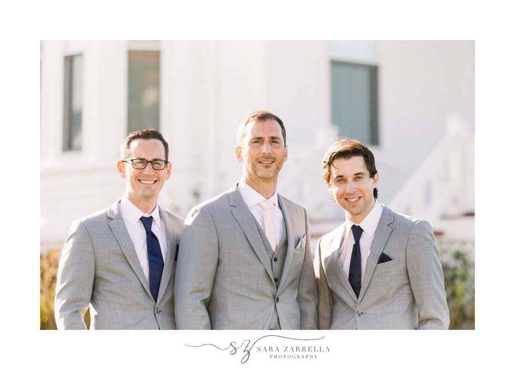 groom stands with groomsmen in grey suits