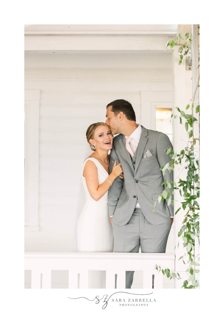 newlyweds stand on porch with ivy colored railing at the Spring House Hotel