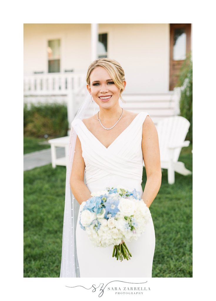 bride stands holding bouquet with blue and white bouquet 