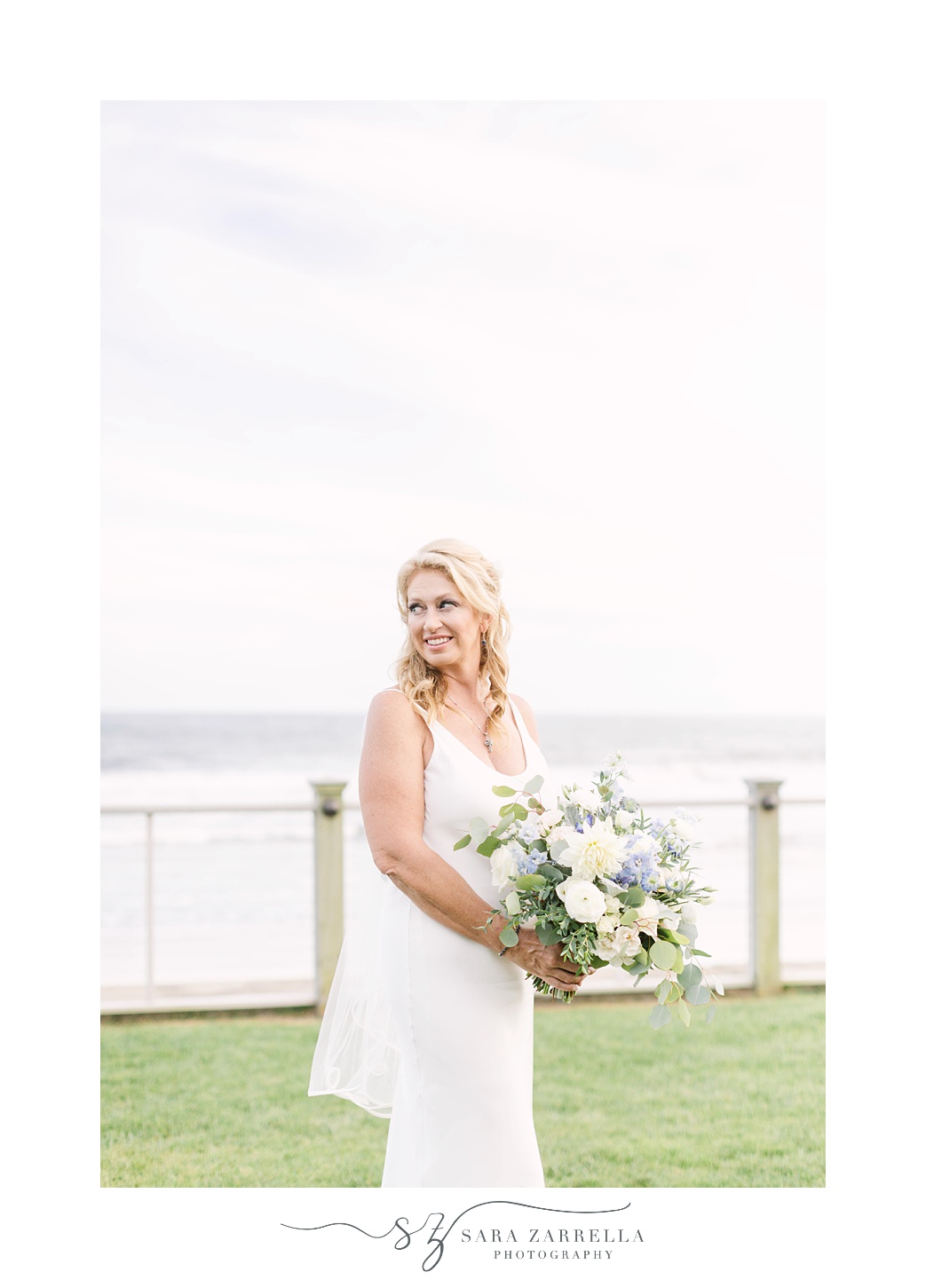 bride holds bouquet and poses by bay at The Dunes Club