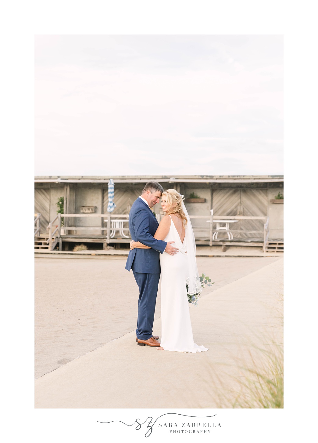newlyweds pose together by wooden building at The Dunes Club