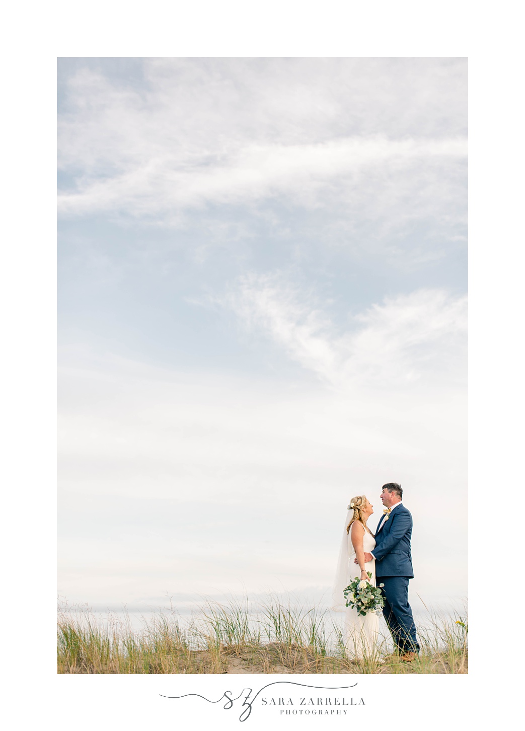 newlyweds stand on the beach outside The Dunes Club