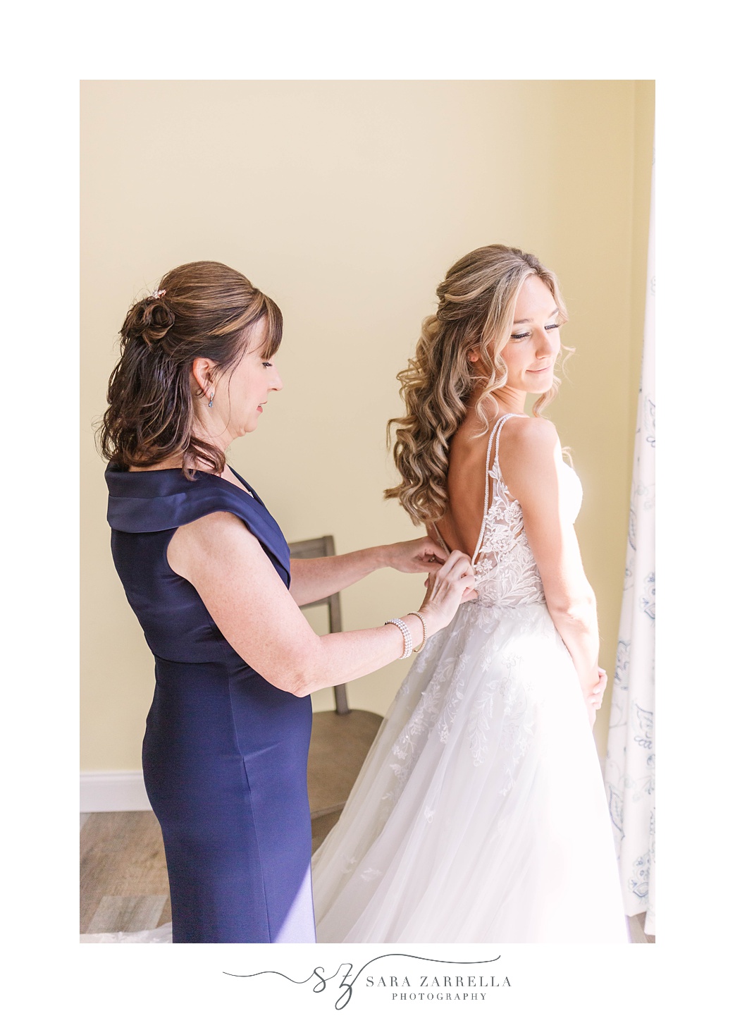 mother helps bride with wedding gown before whimsical garden wedding on Rhode Island farm