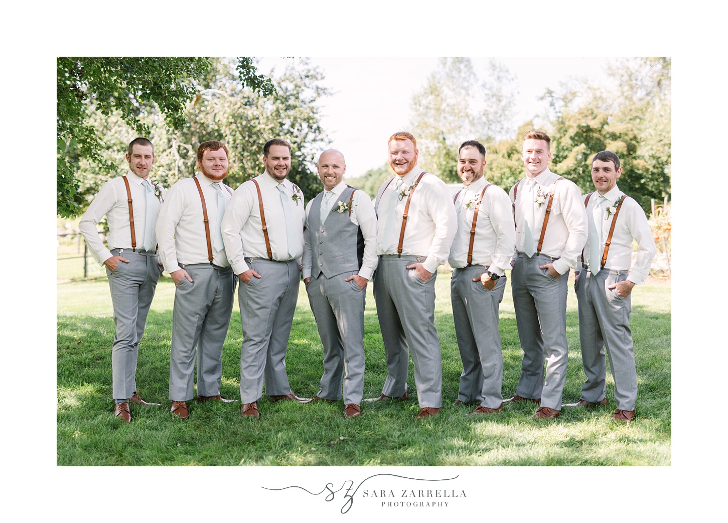 groom stands with groomsmen in suspenders