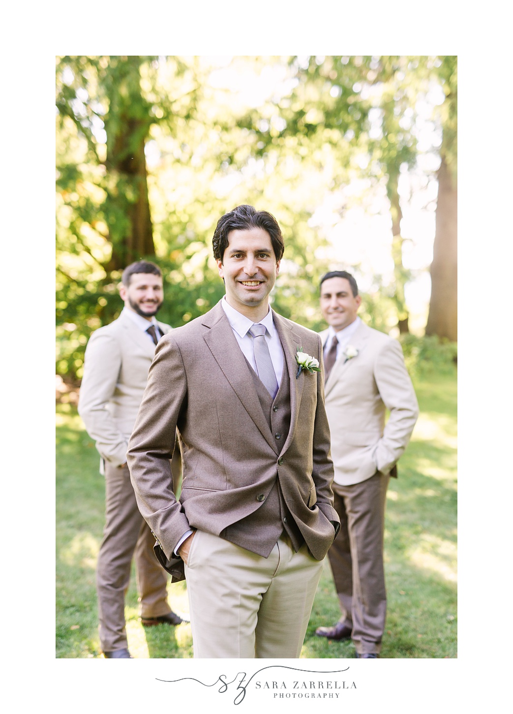 groom stands with groomsmen in woods