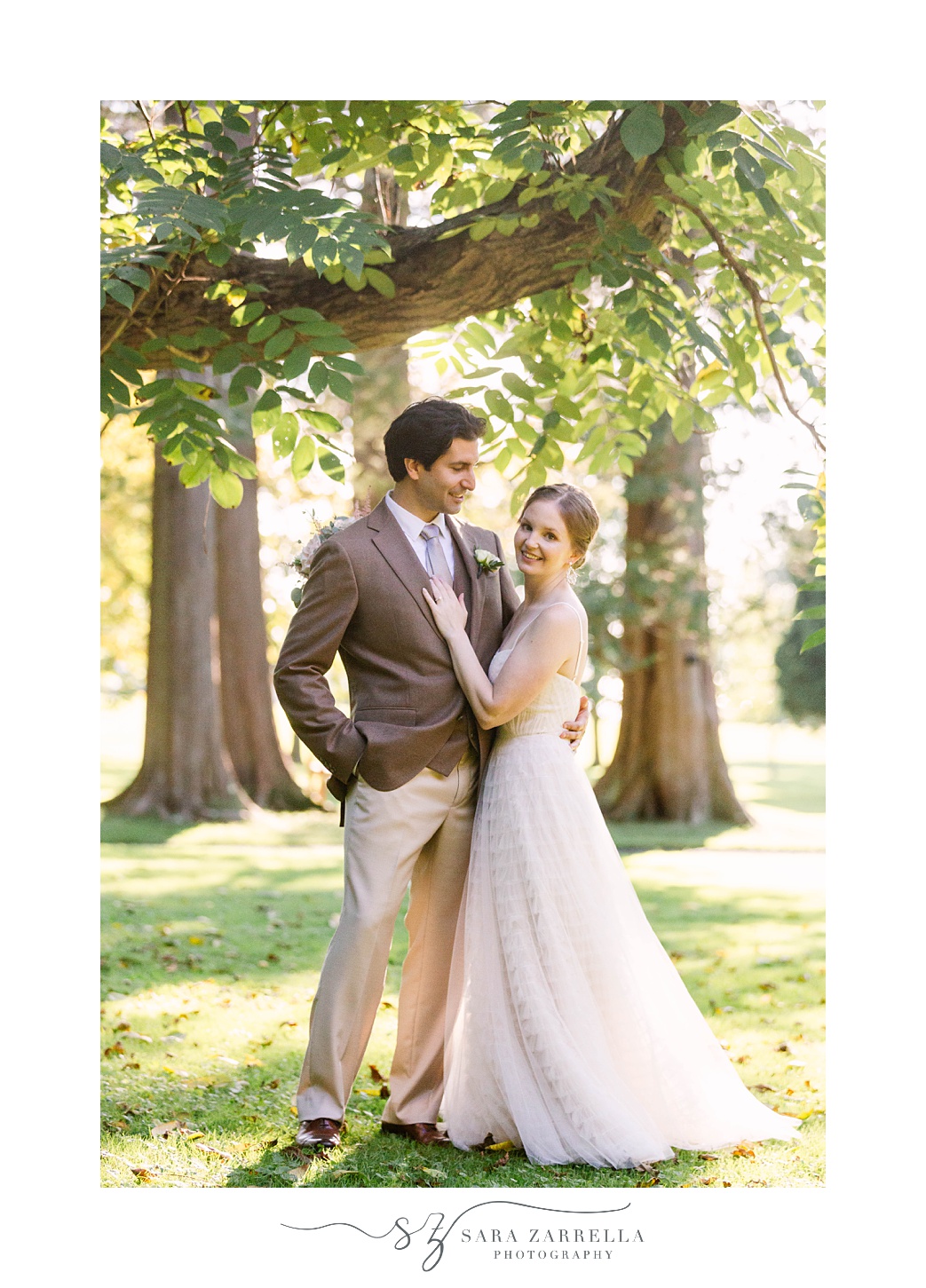 newlyweds pose under trees in field at Blithewold Mansion
