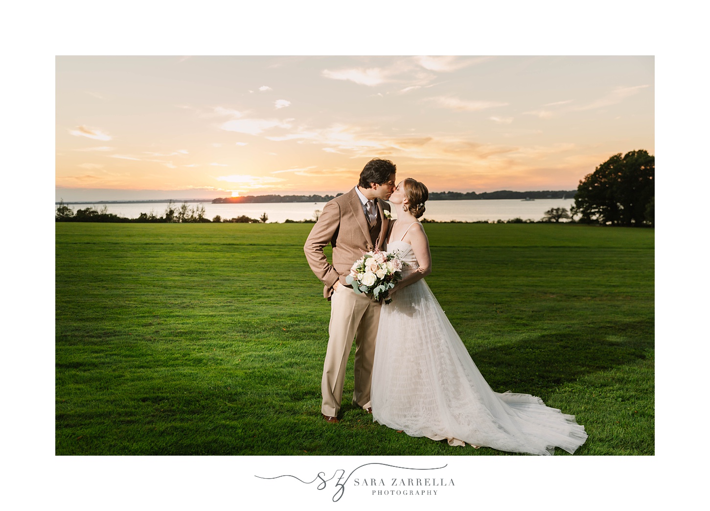 bride and groom kiss at sunset in front of Narragansett Bay
