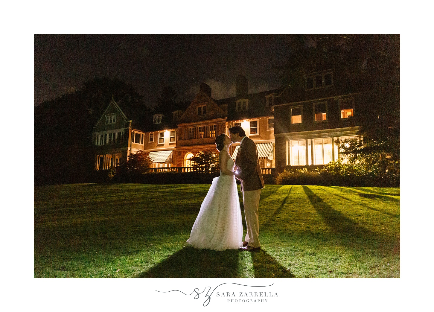 bride and groom kiss outside Blithewold Mansion at night