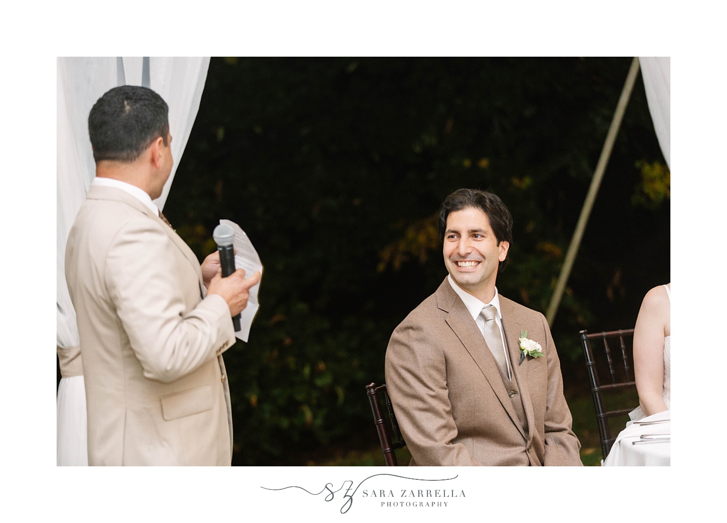 groom smiles at groomsman during wedding toasts