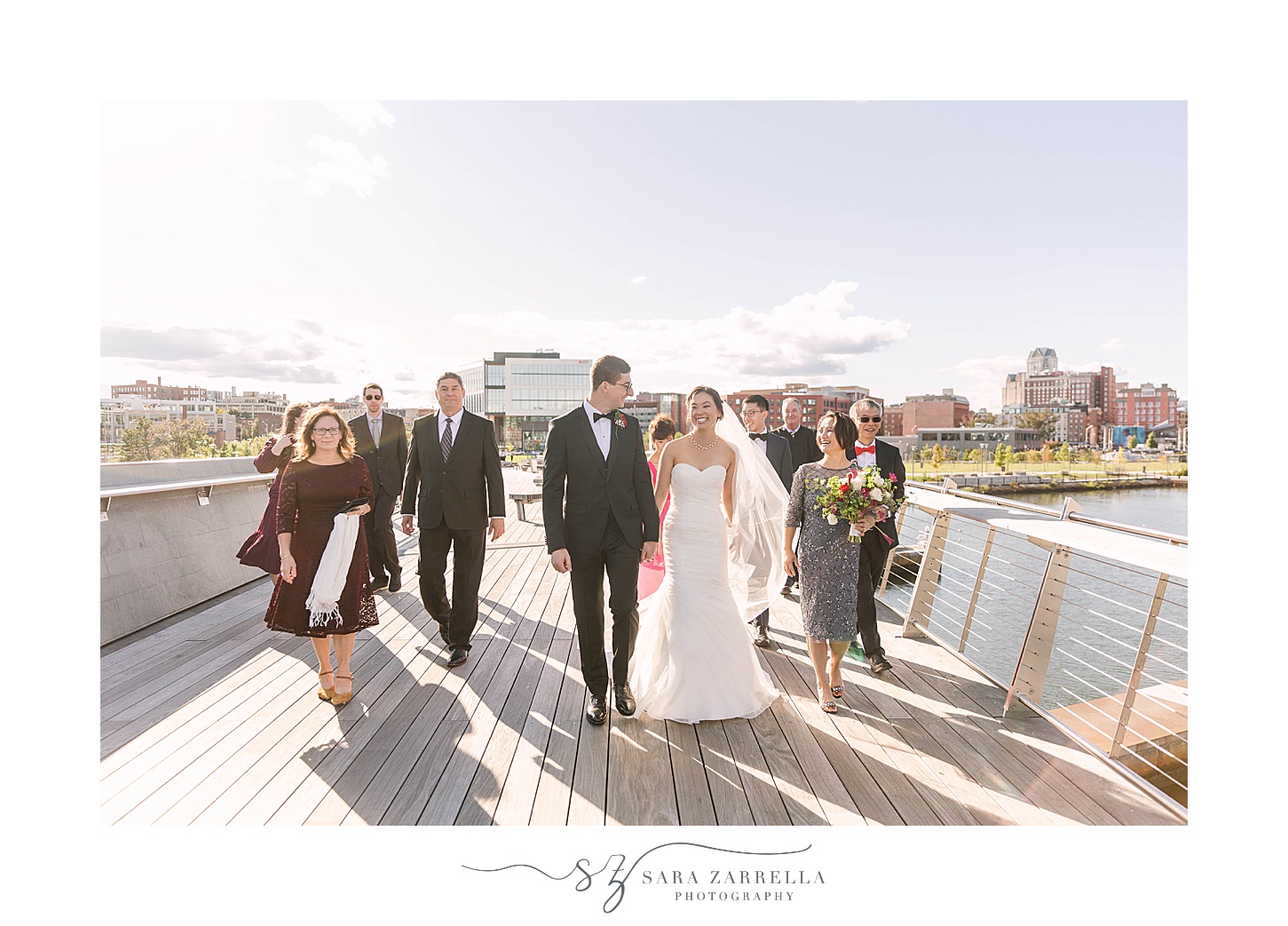 newlyweds walk with family on pedestrian bridge after ceremony