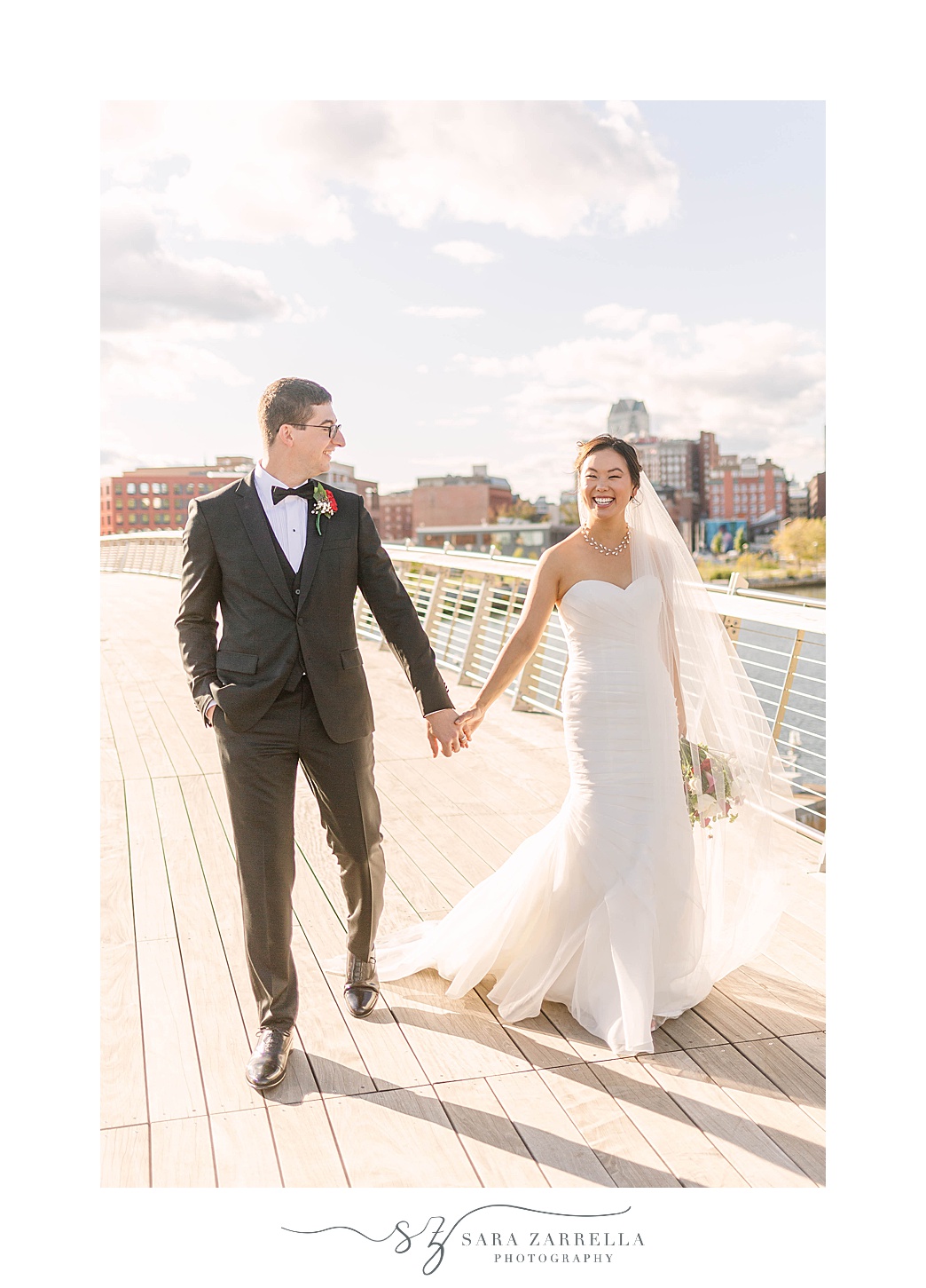 bride and groom walk on bridge during Downtown Providence wedding portraits 