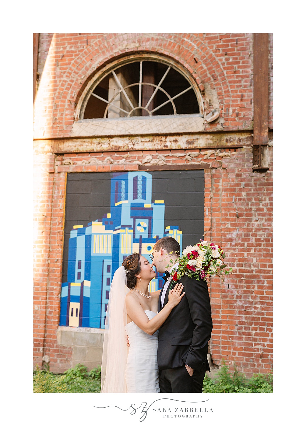 bride and groom kiss by mural in Downtown Providence