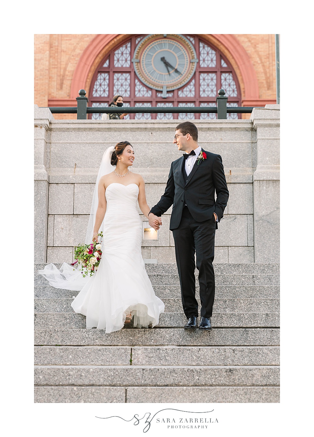 bride and groom walk down steps of historic building 