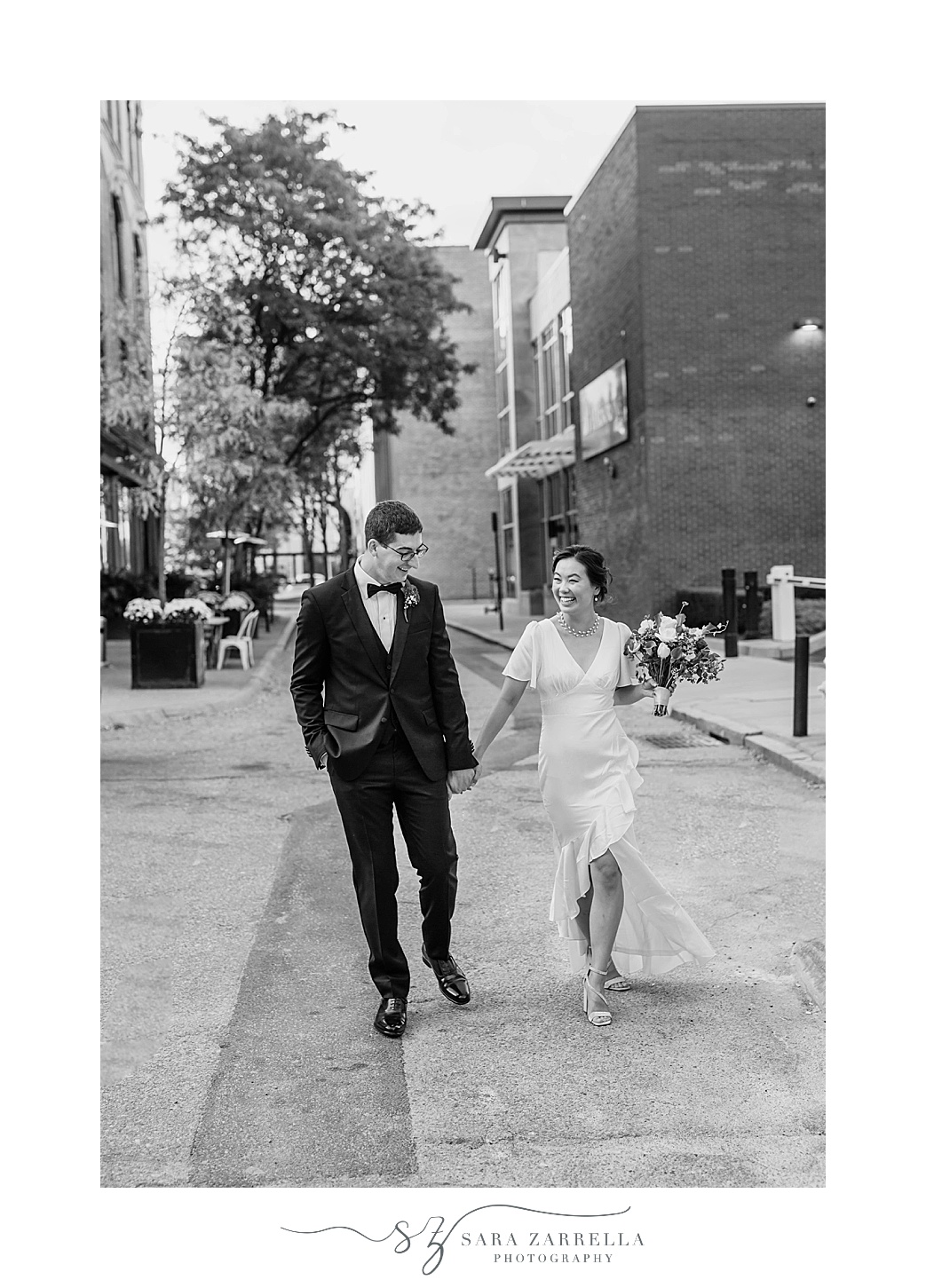 bride and groom hold hands walking down street in Rhode Island 