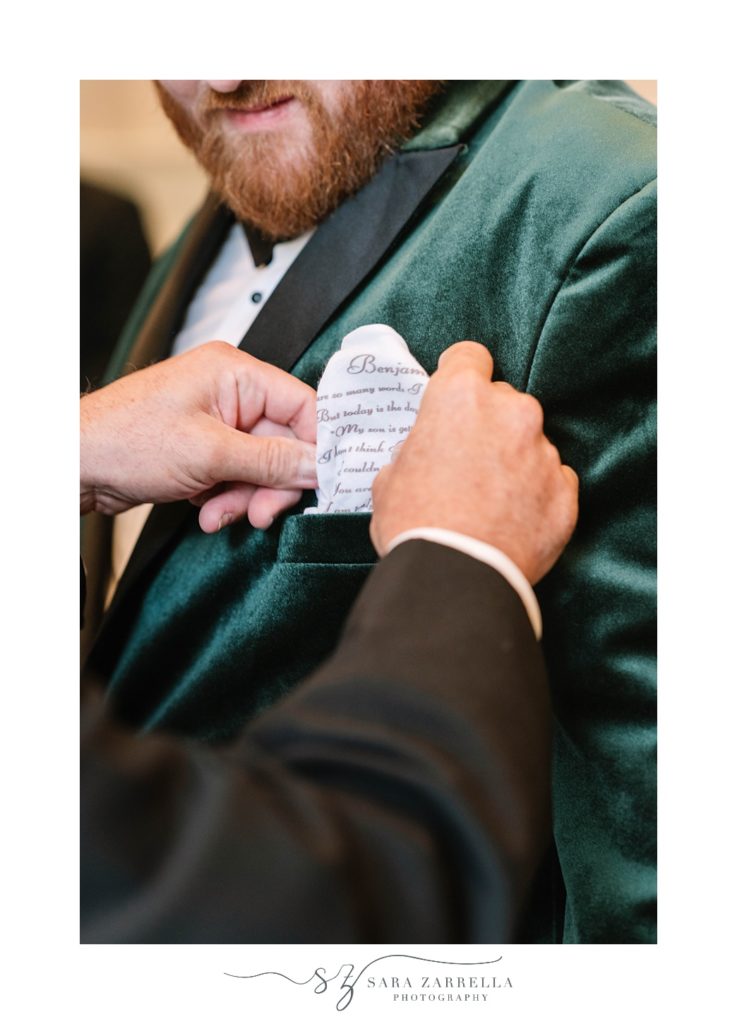 groomsman tucks pocket square into groom's pocket 