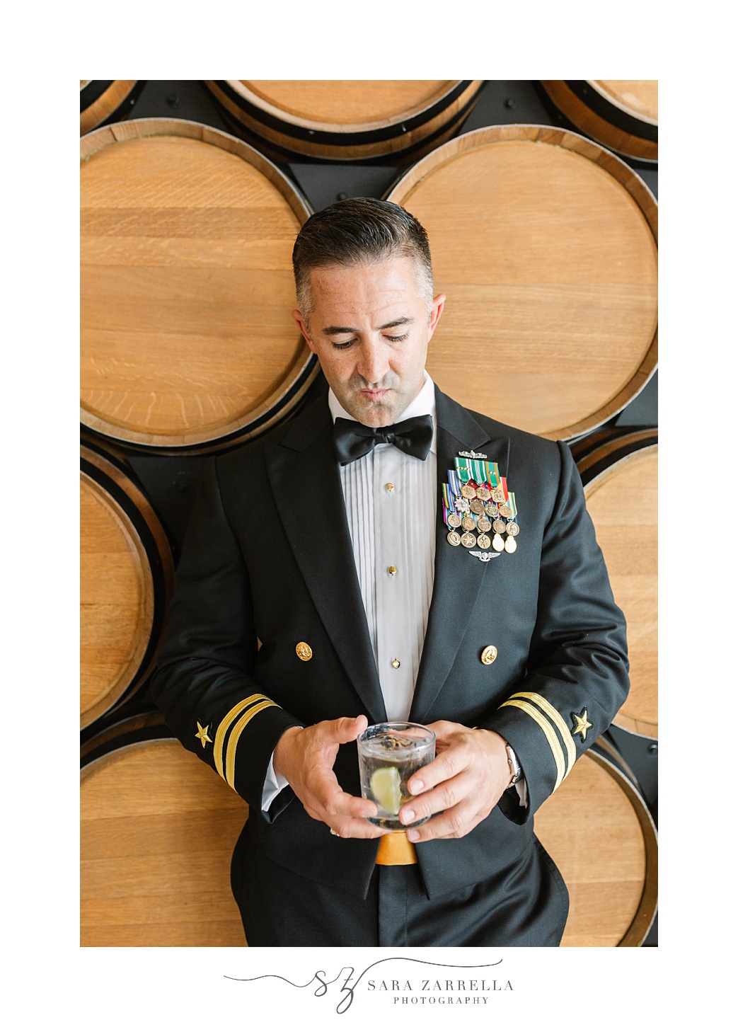 groom holds drink against barrels at Newport Navy Officers’ Club