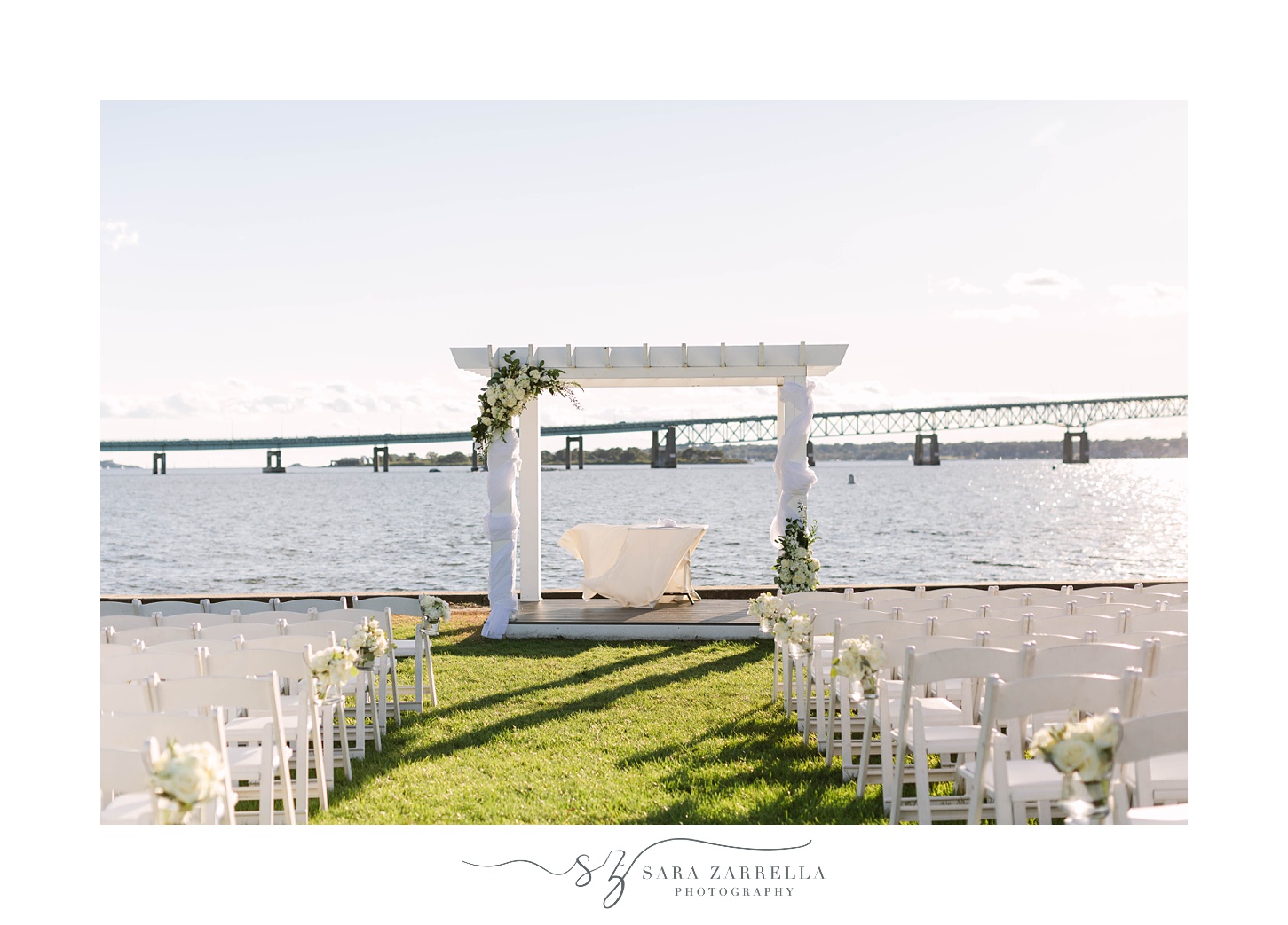 waterfront wedding ceremony under white arbor at the Newport Navy Officers’ Club
