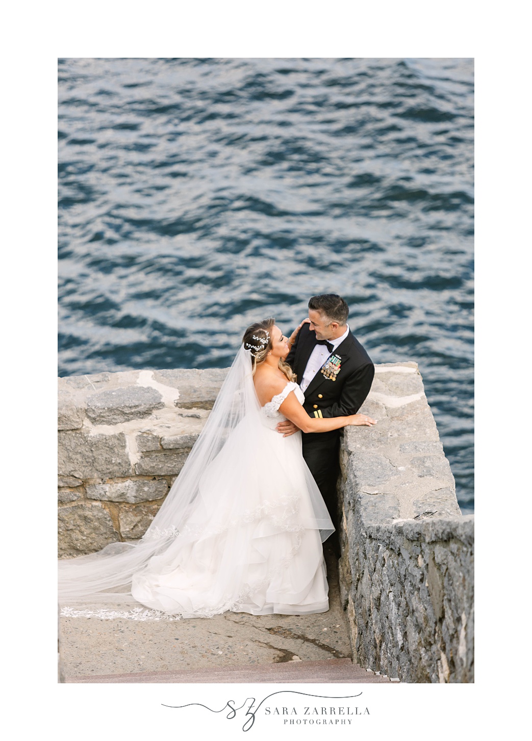 bride hugs groom's arm during photos in Newport on stone steps