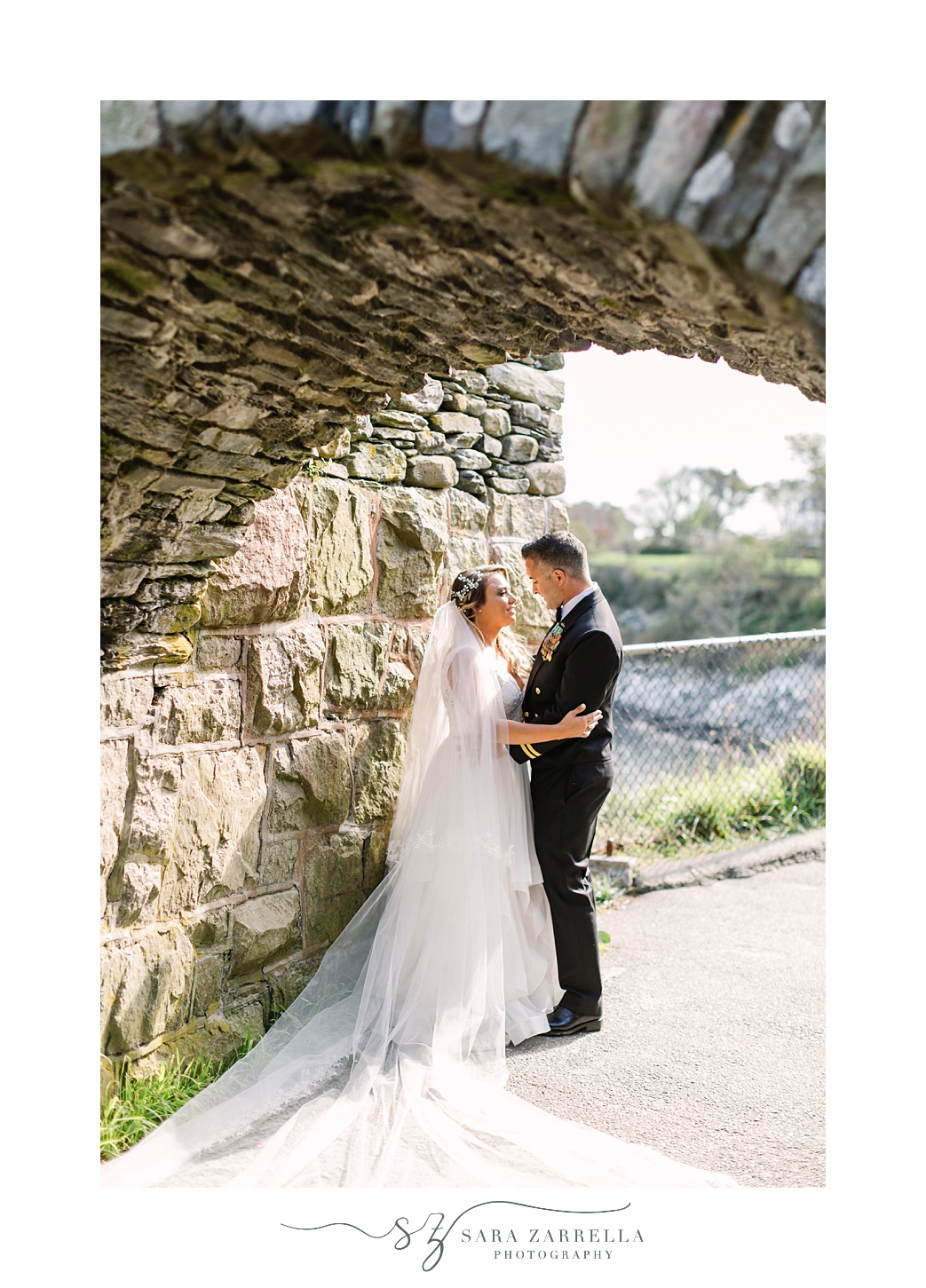 bride and groom pose under stone bridge in Newport RI