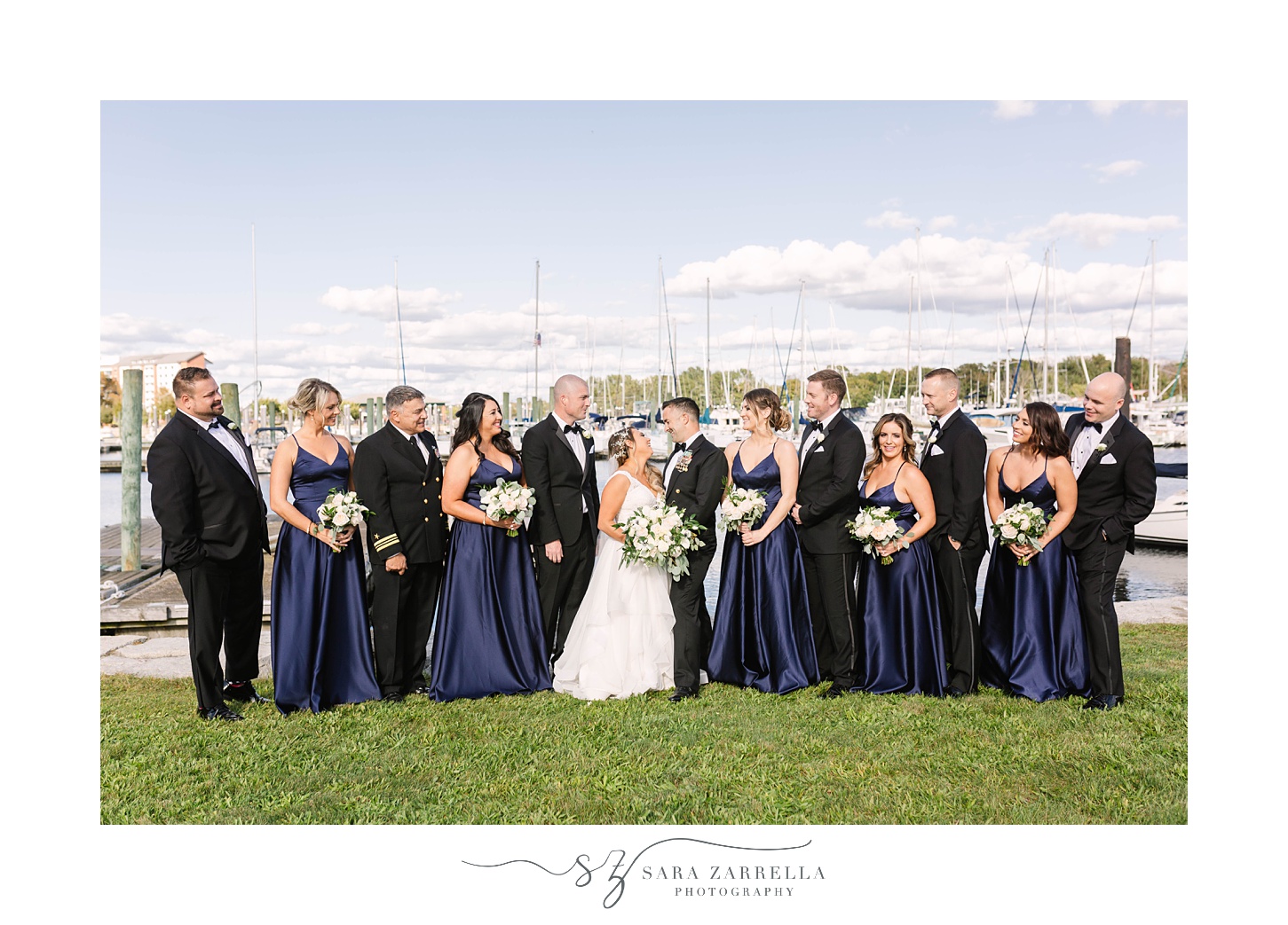 bride and groom kiss while wedding party surrounds them in navy and black