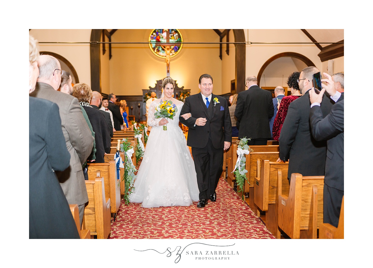 newlyweds walk up aisle after traditional church wedding in Rhode Island