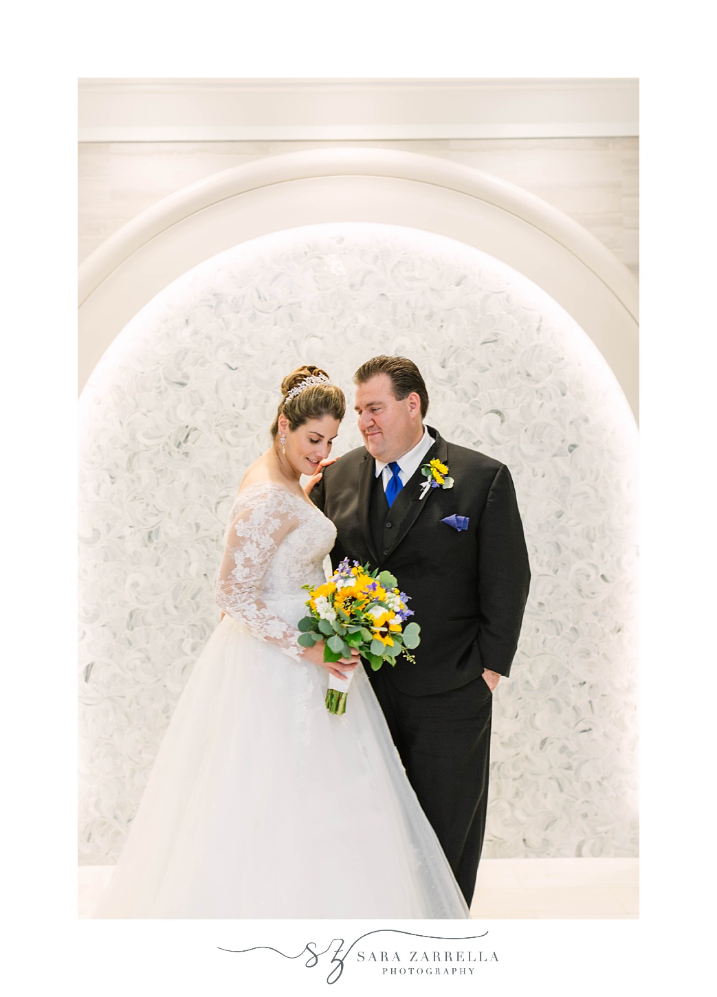 newlyweds pose together in white hallway at Quidnessett Country Club