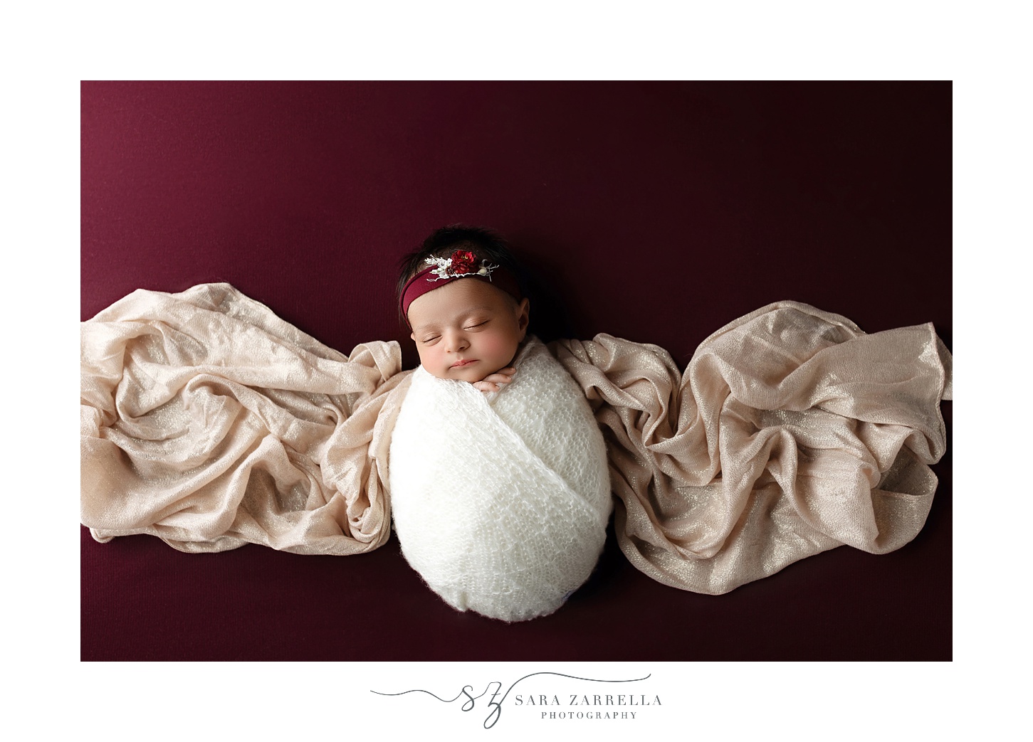 baby sleeps on cream wrap on burgundy backdrop during RI newborn portraits