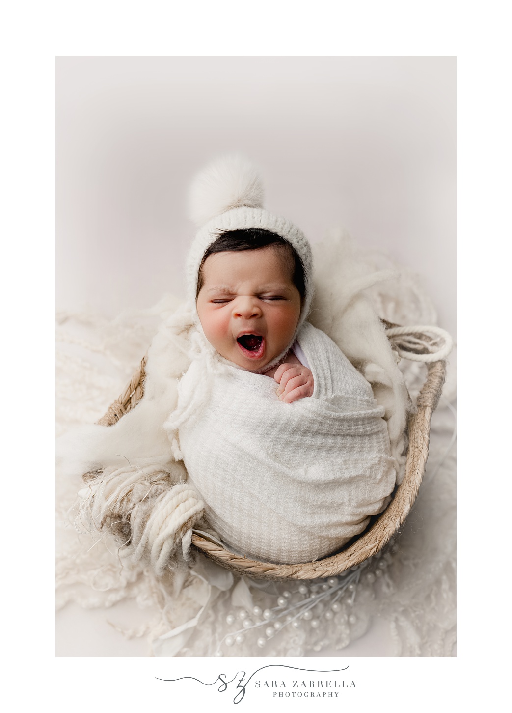 baby sleeps in white blanket and fuzzy hat