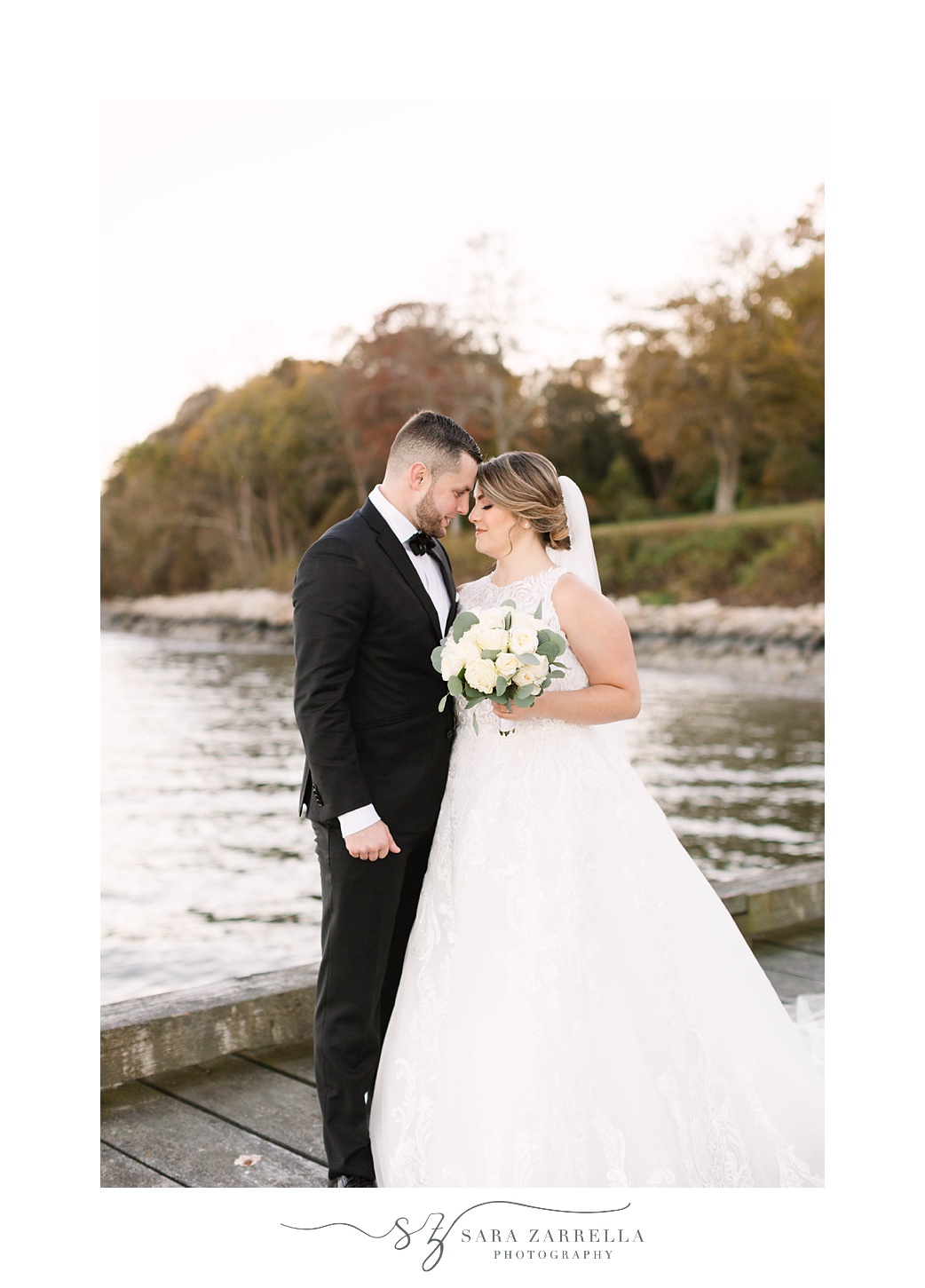 bride and groom hug during fall wedding portraits along the water in Rhode Island 