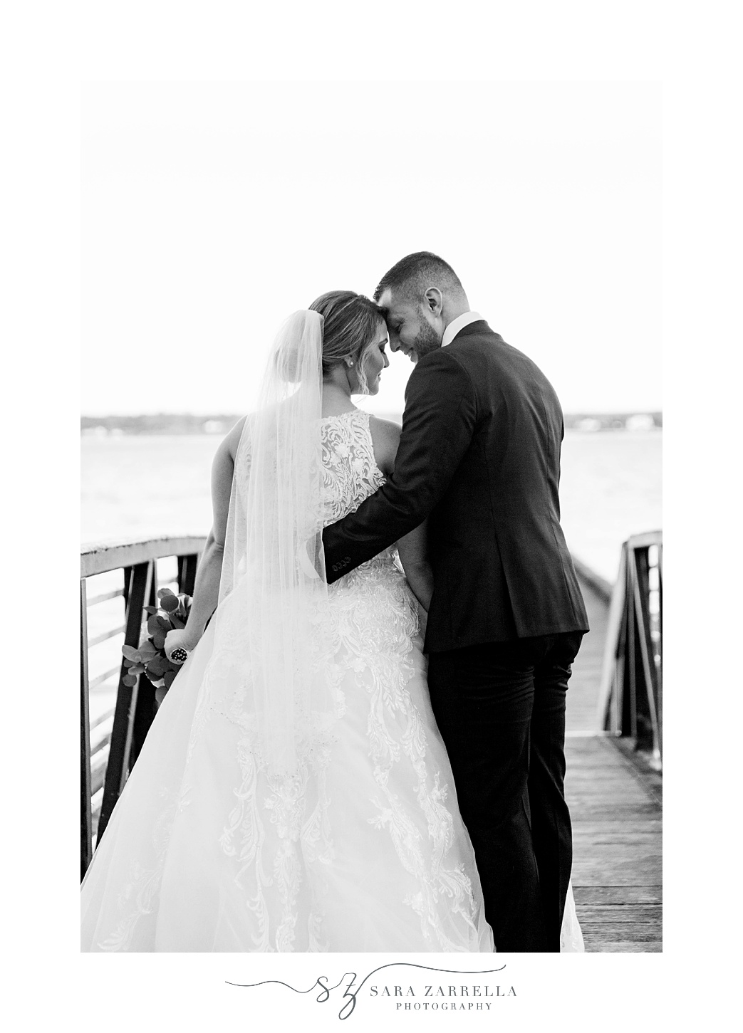 bride and groom hug on pier during RI wedding portraits 