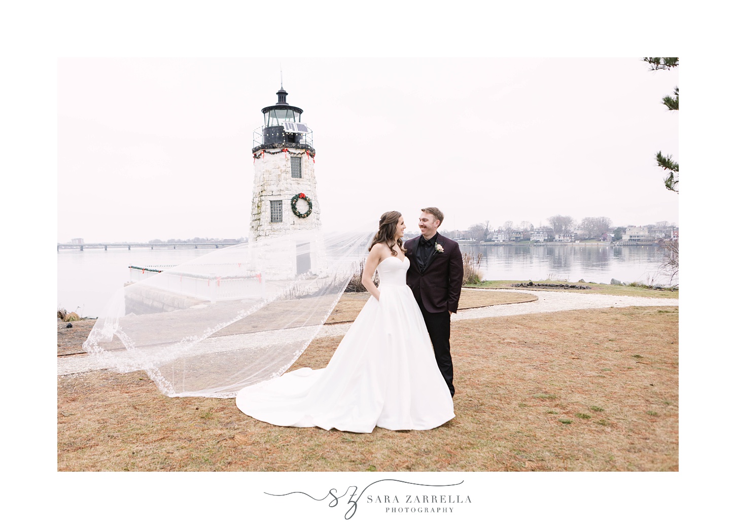  newlyweds pose by lighthouse during New Year’s Eve Belle Mer wedding portraits 