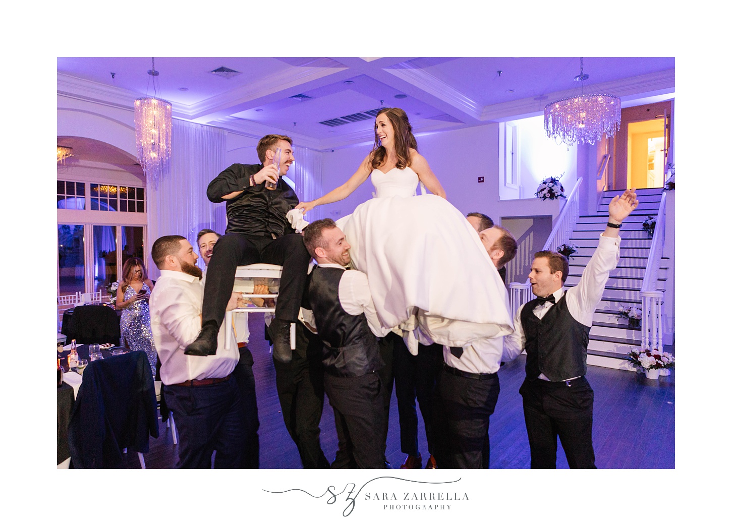 friends lift bride and groom in chairs
