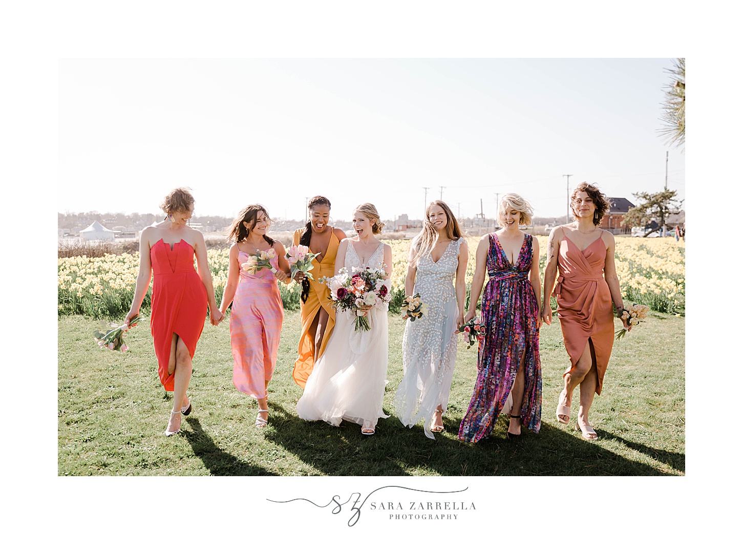 bride walks with bridesmaids in colorful gowns at Newport Beach House