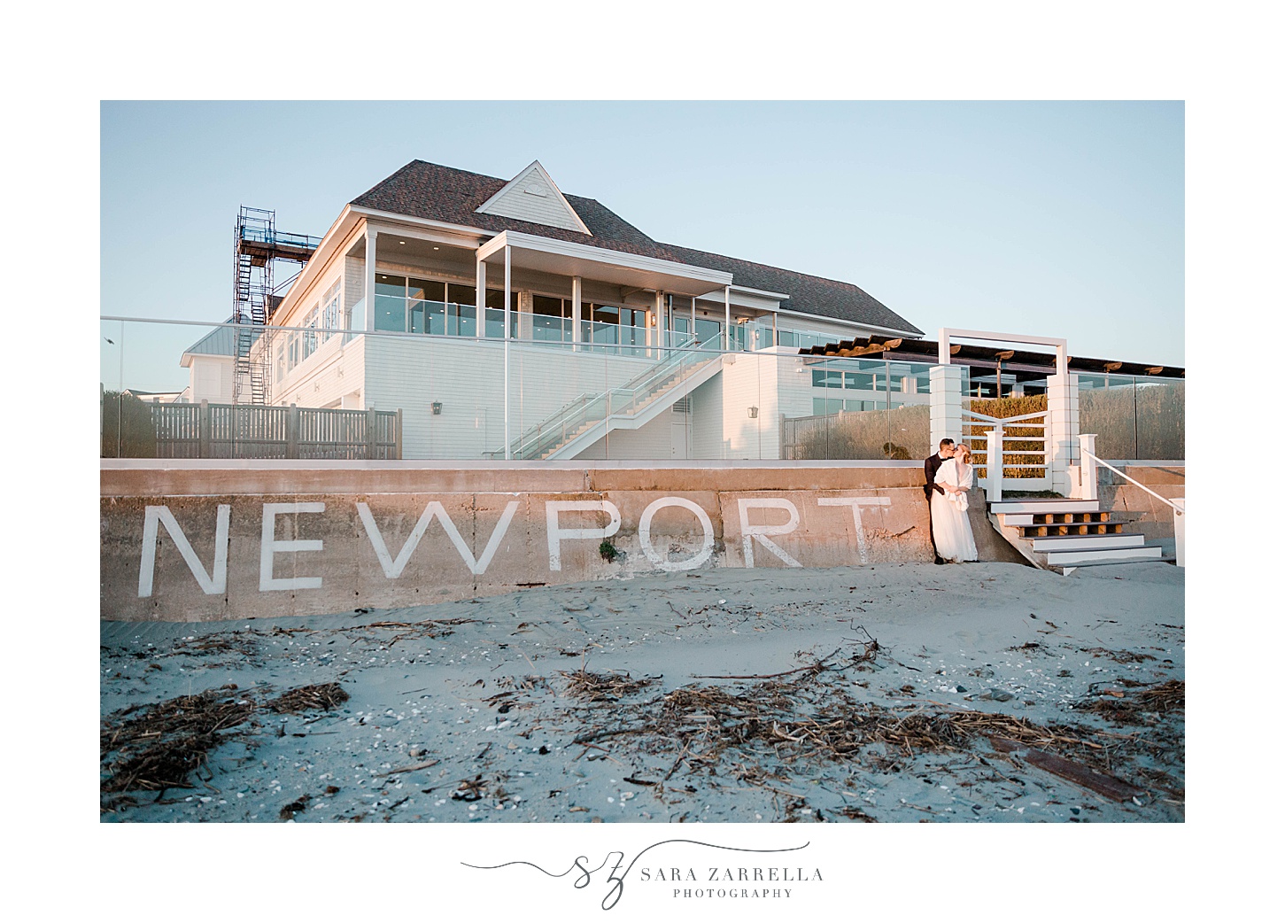 bride and groom pose by sign at Newport Beach House