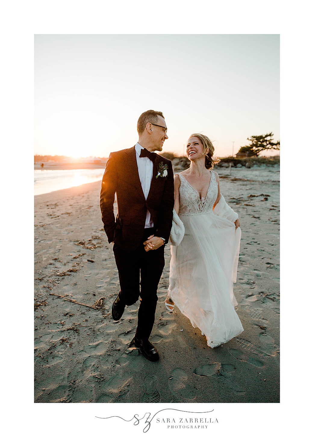 bride looks up at groom smiling during beach portraits 