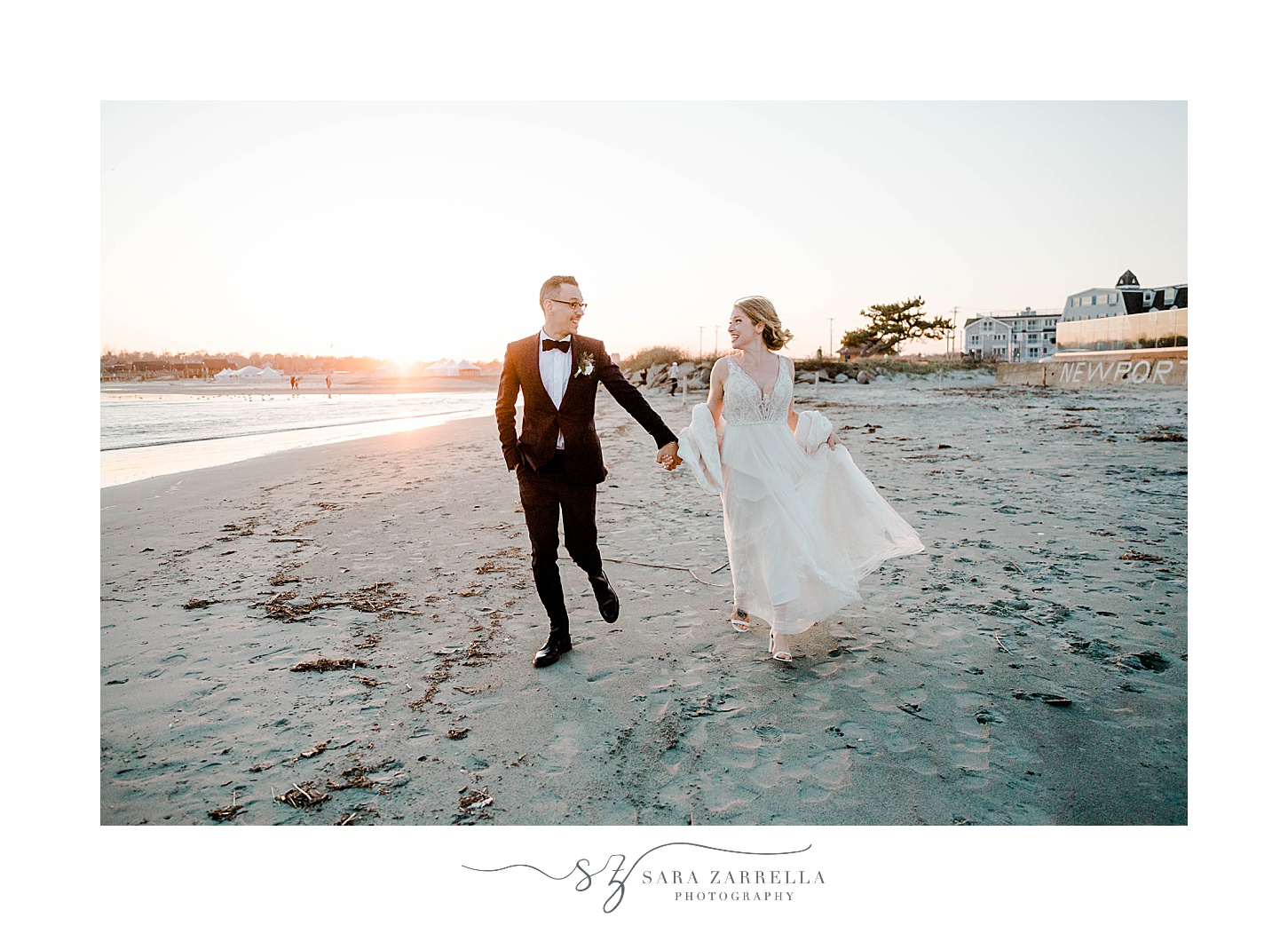 bride and groom hold hands walking on beach in Newport RI