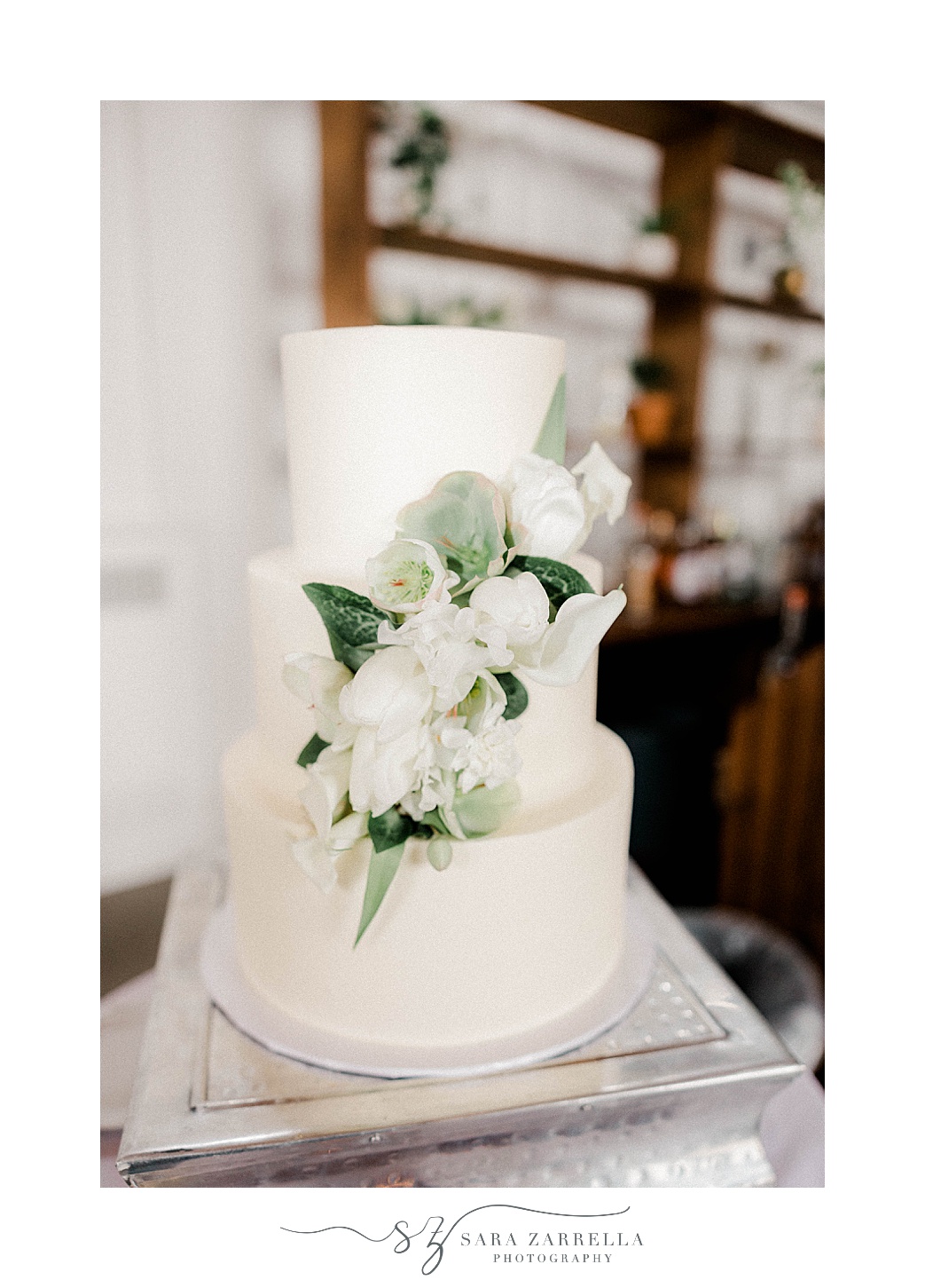 tiered wedding cake with white and green floral details 