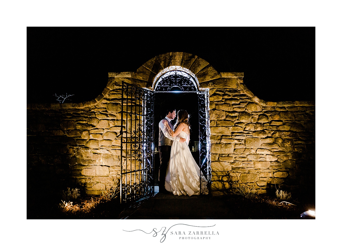 couple stands under stone wall and gate at Shepard's Run