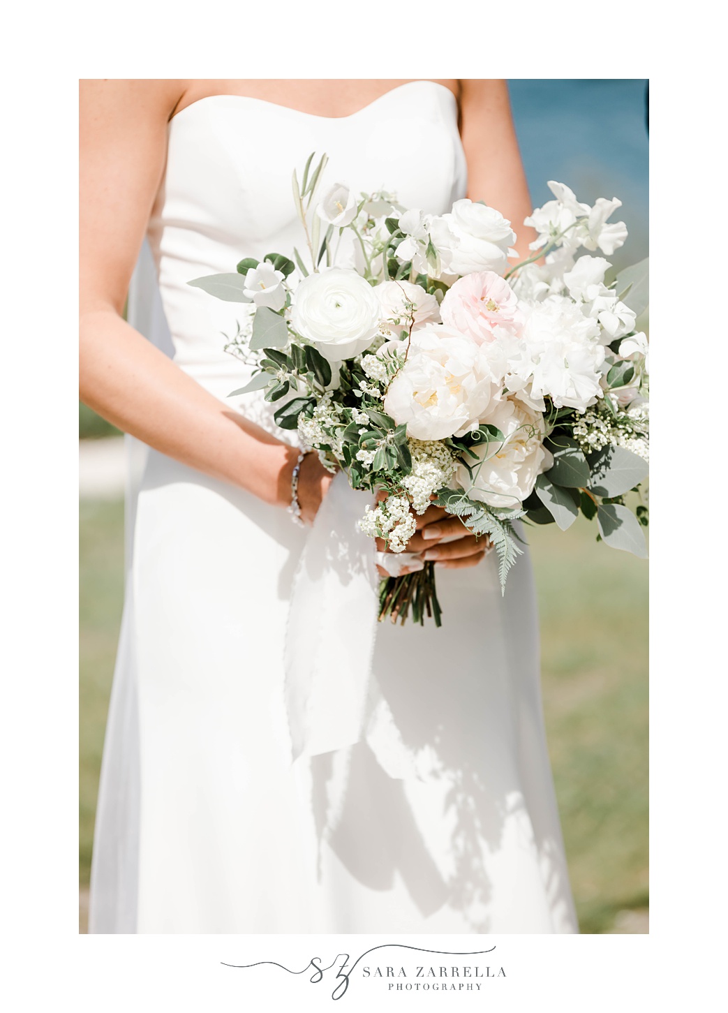 bride holds bouquet of white and pale pink flowers at Gurney's Resort