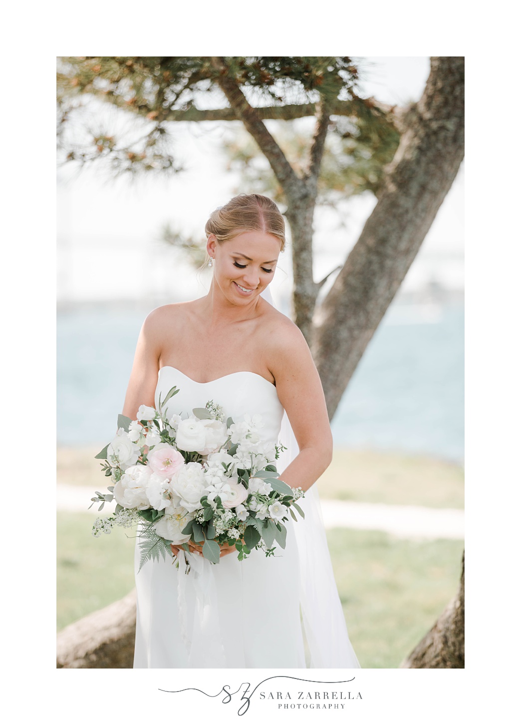 bride smiles down over bouquet during Gurney's Resort wedding portraits 