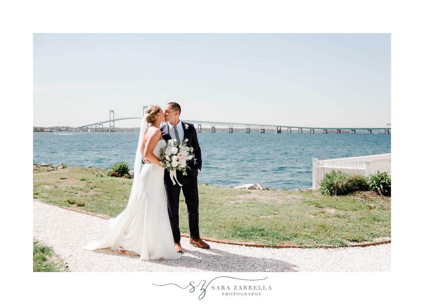 newlyweds kiss with Newport Bridge behind them