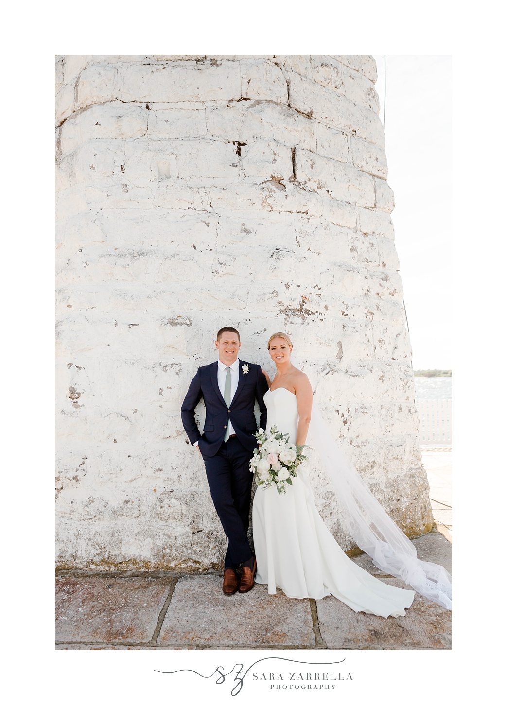 bride and groom stand by white lighthouse in Newport RI