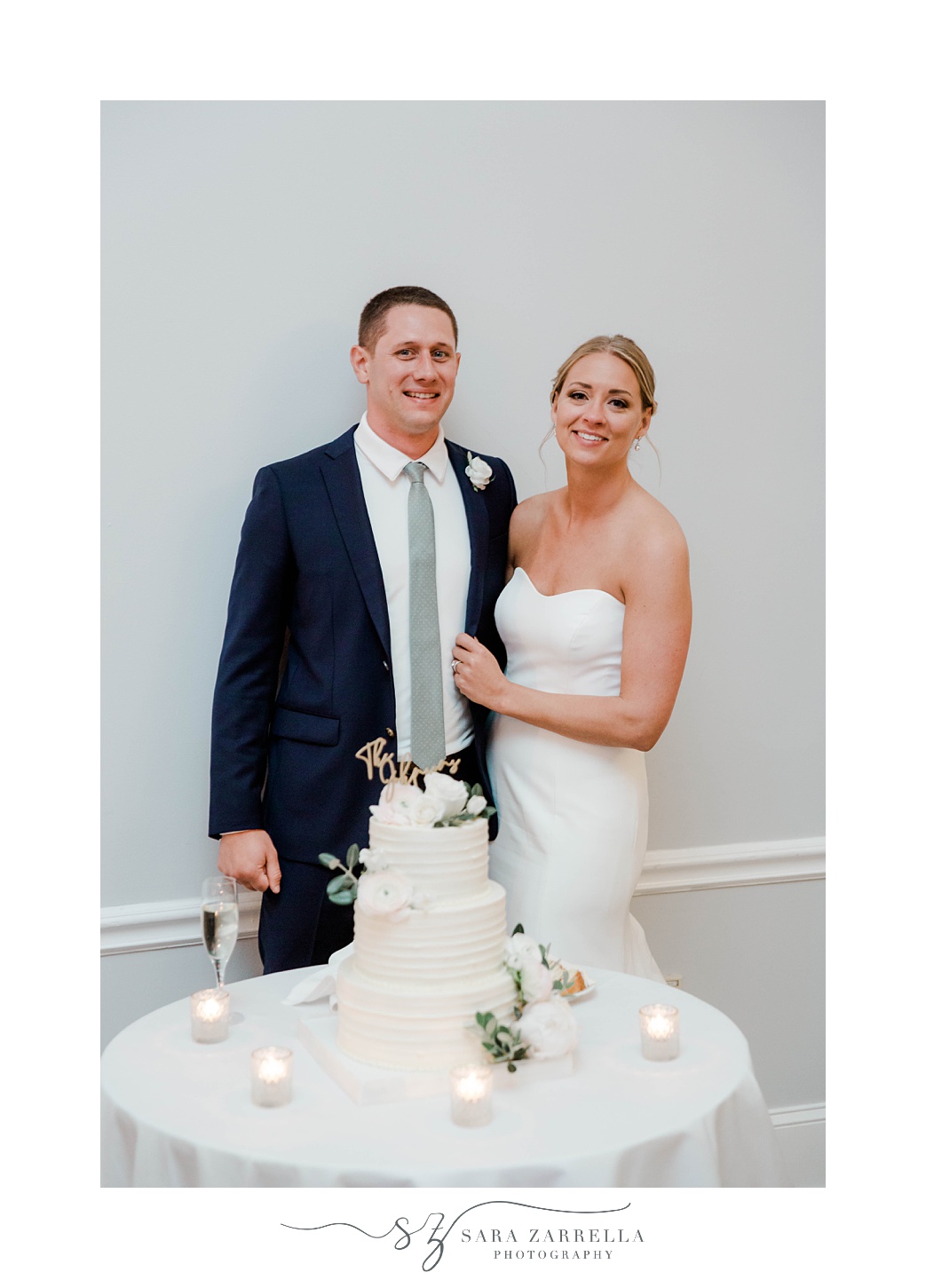 newlyweds pose by wedding cake during Newport RI wedding reception 