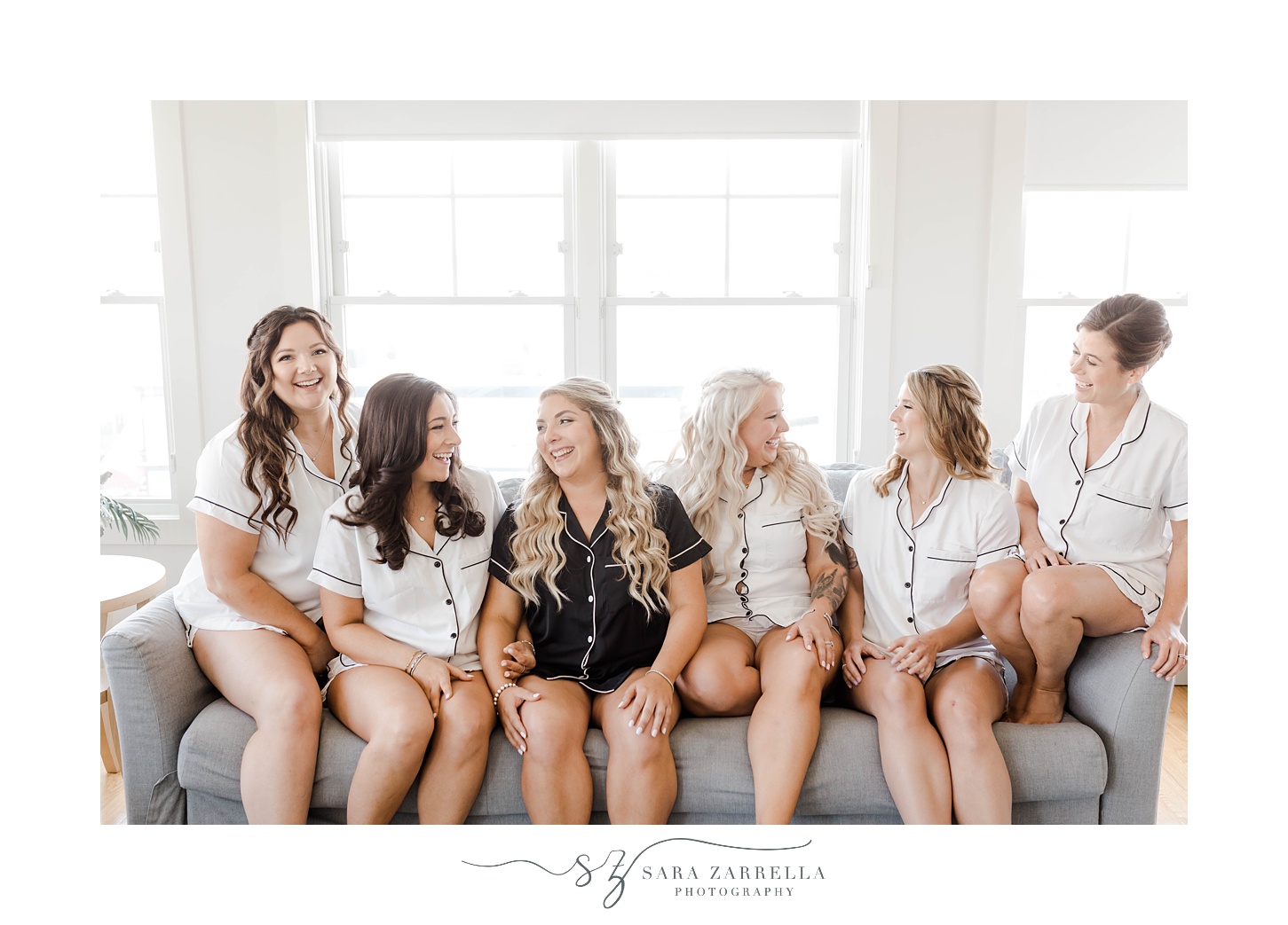 bride sits on sofa with bridesmaids in matching pajamas at Newport Beach House