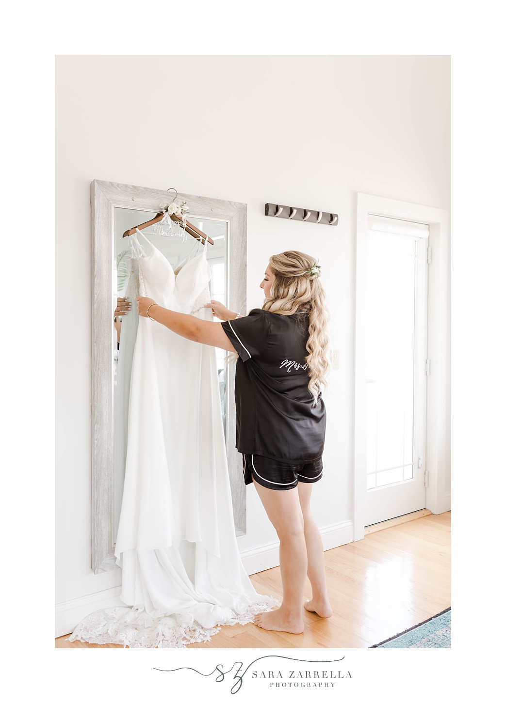 bride looks at wedding gown hanging on door at Newport Beach House