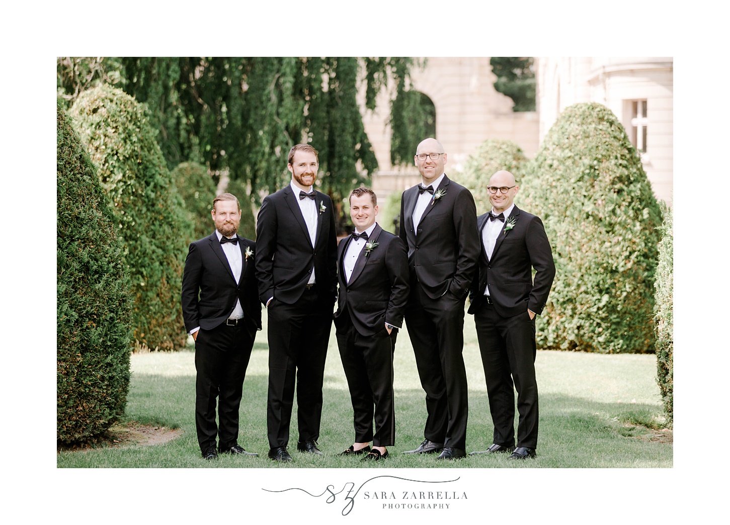 groom stands with groomsmen on lawn of The Elms