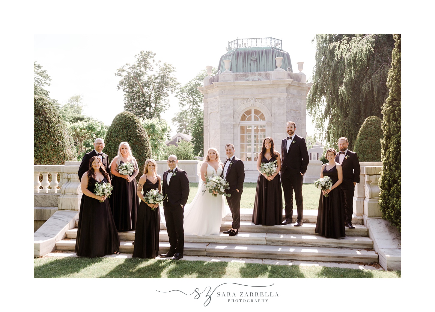 newlyweds stand on staircase at The Elms with wedding party in black