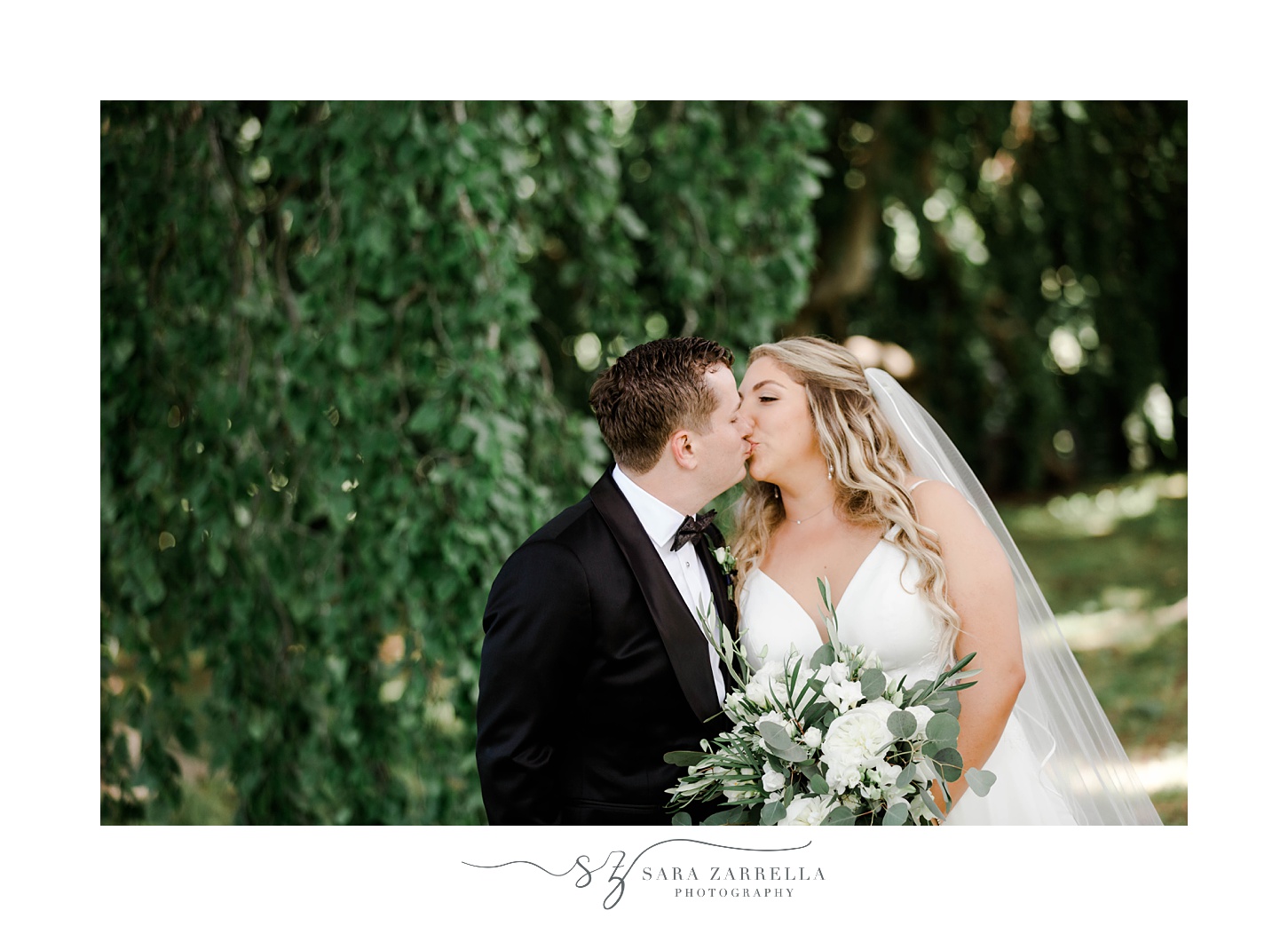 bride and groom kiss against green tree at The Elms
